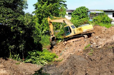 İnşaat alanında kazıcı. Yerdeki kazıcı. Kazıcılar yağmur mevsiminden önce suyu boşaltmak için tıkalı kanallar kazıyorlar..