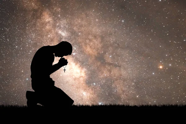 Betender Mann Mit Kreuz Auf Dem Hintergrund Der Sternenklaren Nacht lizenzfreie Stockfotos