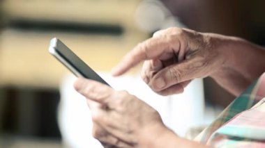 Taşınabilir bir işte çalışan yaşlı bir kadının buruşuk elinin yakın plan çekimi.