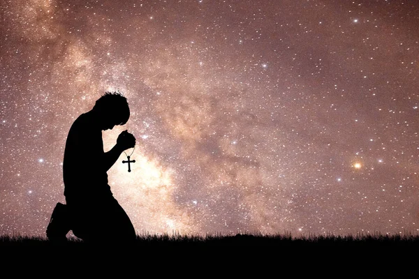 星の夜の背景に十字架の男を祈る — ストック写真