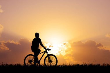 Akşamları çayırda egzersiz yapan bisikletçi silueti, sağlık hizmeti konsepti