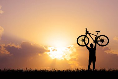 Akşamları çayırda egzersiz yapan bisikletçi silueti, sağlık hizmeti konsepti
