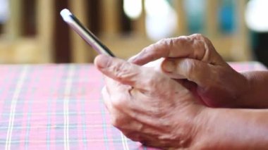 Slow Motion 4 x Yaşlılar cep telefonlarından alışveriş yapıyor. Yaşlı bir insanın elleri cep telefonu kullanıyor..
