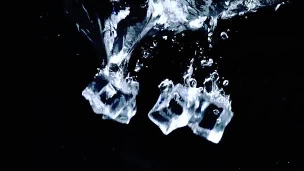 4X置于水中的冰立方体缓慢运动 在黑色背景上有气泡 — 图库视频影像