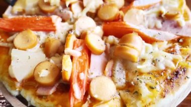 Hamur, sosis, jambon, ananas ve peynirden oluşan ağız sulandıran bir pizza..