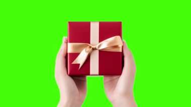 Yeşil arka planda hediye kutusunu tutan bir kadının elleri. Sevgililer Günü, Uluslararası Kadınlar Günü, doğum günü, tatil konsepti