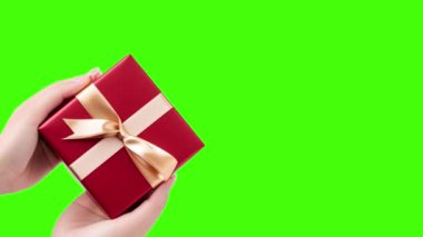 Yeşil arka planda hediye kutusunu tutan bir kadının elleri. Sevgililer Günü, Uluslararası Kadınlar Günü, doğum günü, tatil konsepti