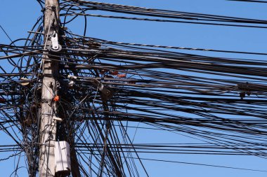 Mavi arka planda kabloları olan elektrik direği