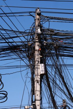 Mavi arka planda kabloları olan elektrik direği