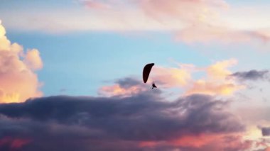 Bulutların üzerinde uçan paraglider silueti 