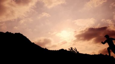 Dağ yürüyüşü antrenmanı yapan bir adamın silueti.
