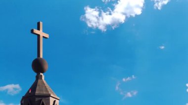 Mavi gökyüzüne karşı hareket eden bulutlarla haçlı kilise 
