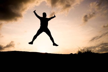 Bir insanın silueti dramatik bir günbatımı gökyüzüne atlıyor, özgürlüğü ve macerayı simgeliyor..