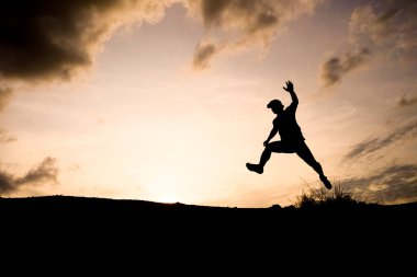 Gün batımında gökyüzüne doğru atlayan bir insanın silueti özgürlüğü ve macerayı simgeliyor..