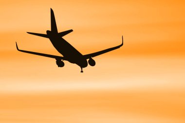 Canlı turuncu bir günbatımı gökyüzüne doğru uçan bir uçağın silüeti seyahat ve havacılık teması için mükemmel..