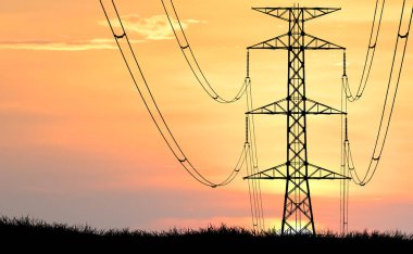 Yüksek voltajlı elektrik hatları ve iletim kulesinin silueti canlı bir günbatımı gökyüzüne karşı, enerji ve altyapıyı simgeliyor..