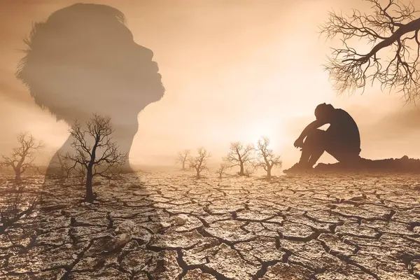 stock image Double exposure image of a person and a barren landscape with cracked earth and bare trees at sunset, evoking themes of solitude and environmental issues.