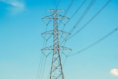 Yüksek voltajlı elektrik hattı kulesi açık mavi gökyüzüne karşı, endüstriyel altyapı ve enerji aktarımını gösteriyor.