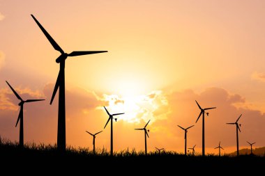 Siluetli rüzgar türbinleri canlı bir günbatımı gökyüzüne karşı yenilenebilir enerji ve sürdürülebilir güç üretimini sembolize ediyor..
