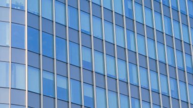 Şehir manzarasında yansıtıcı pencereleri olan modern cam ofis cephesine yakın plan, çağdaş mimari sergileniyor..