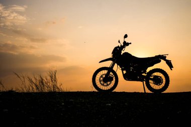 Çarpıcı bir motosiklet silueti güzel bir gün batımına karşı çekilmiş, macera ve özgürlük hissi uyandırıyor..