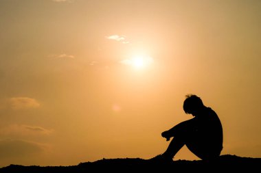 Yalnız bir figür, çarpıcı bir gün batımına karşı düşüncelere dalmış, huzurlu ve yansıtıcı bir sahne yaratıyor..