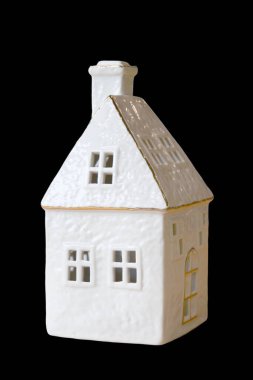 Altın aksanlı, minimalist beyaz bir seramik ev süsü. Detaylı pencereler ve siyah arka planda duran bir baca..