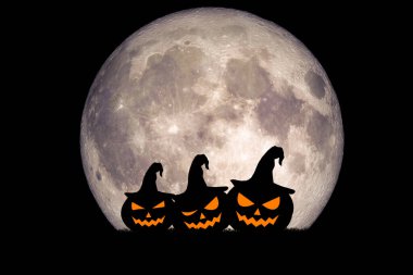 Üç oyulmuş cadı şapkalı balkabağı dolunaya karşı siluetli, ürkütücü bir Cadılar Bayramı sahnesi yaratıyor..