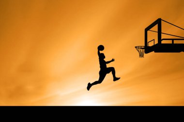 Bir basketbol oyuncusunun silueti havada, topu canlı turuncu bir günbatımı gökyüzüne atmak için zıplıyor, arka planda basketbol potası var..