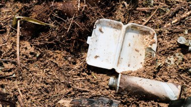 Çevre kirliliğini ve uygun atık yönetimi ihtiyacını vurgulayarak, zemini kirleten plastik ve metal atıklarına yakın çekim.