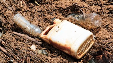 Şişeler ve kaplar da dahil olmak üzere plastik atıklara yakın çekim, doğal bir çevreyi kirletmek, çevreye çöp atmanın ekosistemler üzerindeki etkisini vurgulamak.