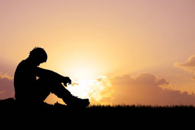 Gün batımında çimlerin üzerinde canlı bir gökyüzü ve bulutlarla huzurlu bir atmosfer yaratan huzurlu bir insan silueti..