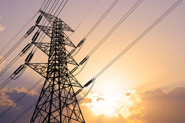 Yüksek voltajlı elektrik hatları canlı bir günbatımı gökyüzüne karşı siluetlendi. Teknoloji ve doğanın kesişimlerini gözler önüne seriyor..