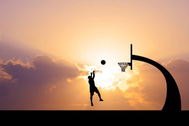 Bir basketbolcunun silueti çarpıcı bir günbatımı gökyüzüne sıçrıyor, sporun ve doğanın güzelliğini vurguluyor..