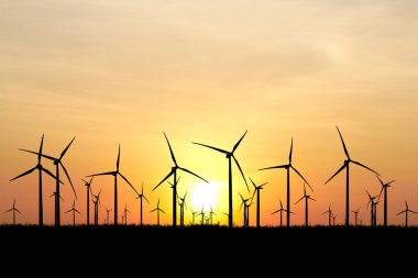 Gün batımında siluetli rüzgar türbinleri ve pürüzsüz düzenleme yolları. Yenilenebilir enerji, çevre ve sürdürülebilirlik temaları için ideal.