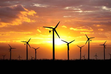 Siluetli rüzgar türbinleriyle dolu, yenilenebilir enerji ve doğal güzellik içeren bir rüzgâr çiftliğinde güzel bir günbatımı..