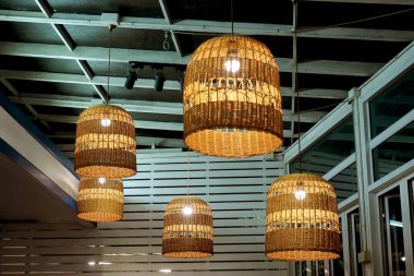 Modern bir açık hava verandasında süslü, örülmüş rattan asma lambaları, geceleri sıcak ve davetkar bir ortam yaratıyor..