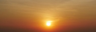 Parlak turuncu ve sarı renkleri olan altın bir günbatımının büyüleyici görüntüsü, sakin ve sakin bir atmosfer yaratıyor..