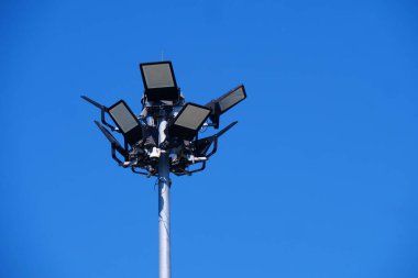 Modern stadyumun projektörleri, açık mavi gökyüzüne karşı duran uzun bir direğe monte edilmişti..