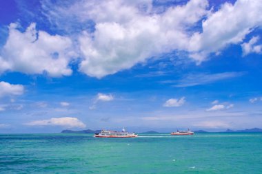Tüylü beyaz bulutlu canlı mavi gökyüzünün altında turkuaz bir denizde iki teknenin yer aldığı güzel bir deniz manzarası..