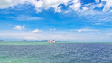 Parlak mavi gökyüzünün altında sakin bir okyanus manzarası, seyahat ve doğa temaları için mükemmel..