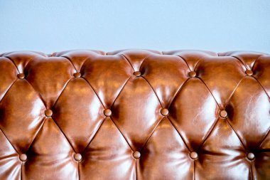 Klasik kahverengi deri koltuğun ayrıntılı görüntüsü düğmeli döşeme, lüks dokusunu ve işçiliğini ön plana çıkarıyor..