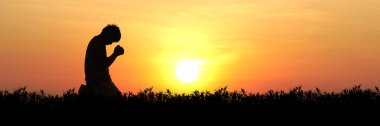Gün batımında canlı turuncu ve sarı gökyüzü ile dua eden, huzur ve yansıma anını yakalayan, siluet içindeki bir insanın huzurlu bir görüntüsü..