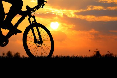 Sersemletici bir günbatımına karşı bir bisikletçinin silueti macera ve özgürlüğün özünü yakalıyor..