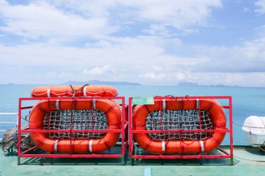 Feribot güvertesindeki canlı turuncu cankurtaranlar büyüleyici bir okyanus ve ada zeminine sahipler. Seyahat ve güvenlik temaları için mükemmel..