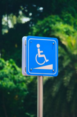 Tekerlekli sandalye sembolü içeren mavi engelli erişilebilirlik işaretinin yakın plan görüntüsü..