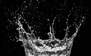 Suyun yüksek hızda yakalanması siyah zemine sıçrar, sıvı hareketi ve dinamik enerjiyi gösterir..