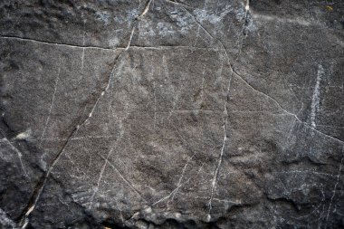 Yıpranmış bir taş yüzeyin detaylı görüntüsü doğal çatlaklar ve dokular sergiliyor, arka plan ya da tasarım elementleri için mükemmel..