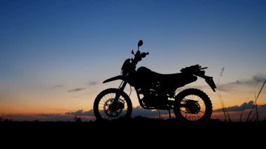 Gün batımının arka planında motosiklet silueti