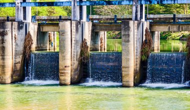 Akan su ve bitki örtüsüyle bir su barajına yakın çekim, doğal ortamda endüstriyel mimariyi gözler önüne seriyor..
